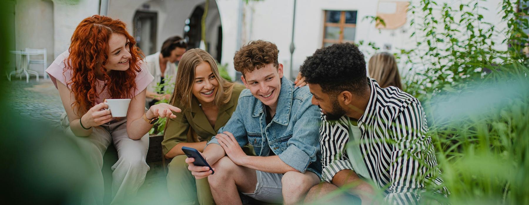 a group of people sitting at a table looking at a phone